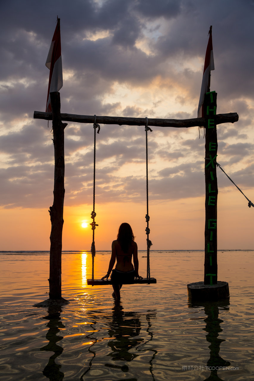 印度尼西亚秋千上观看日落的女性游客剪影