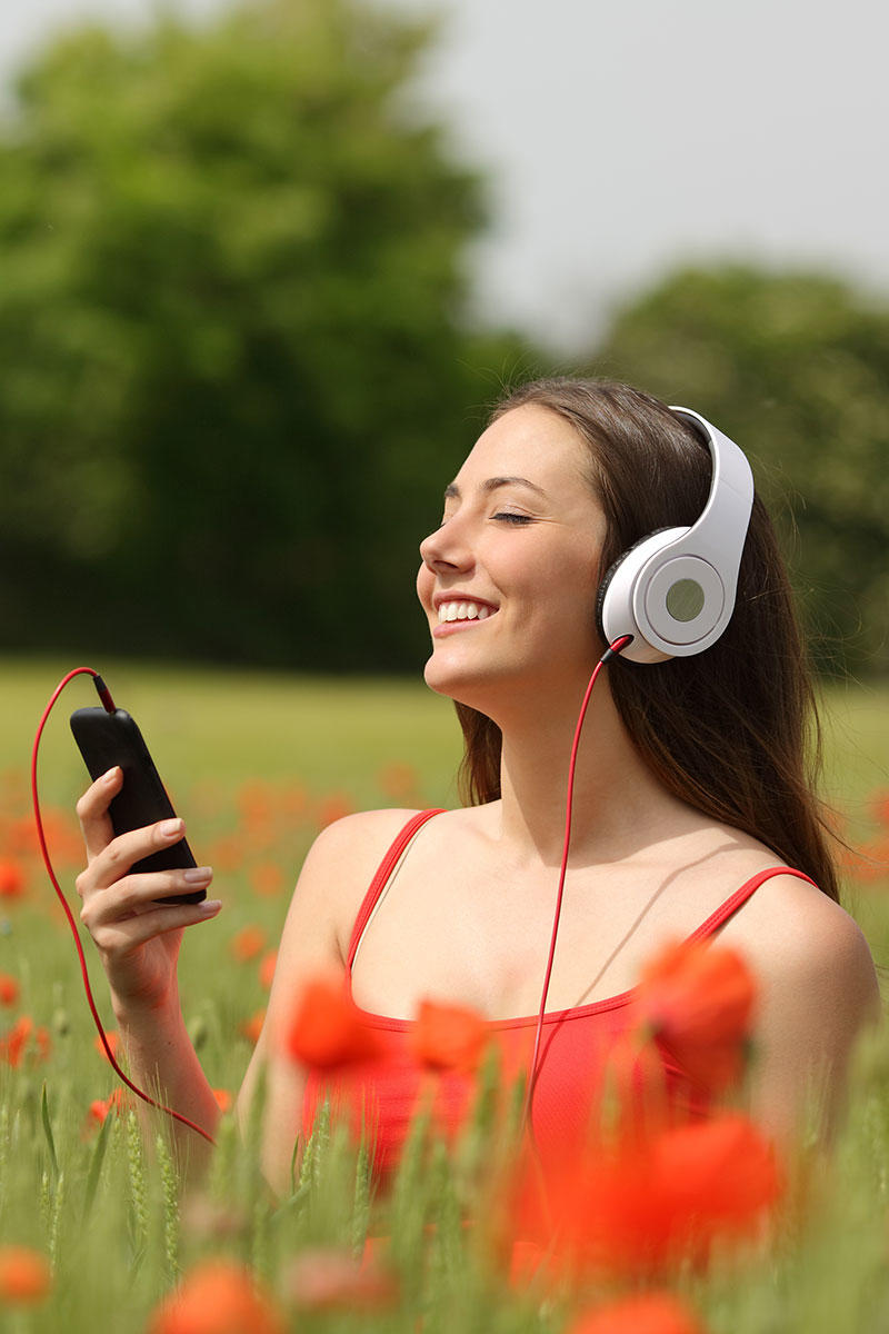 花丛中戴耳机听音乐的外国女性高清摄影图片
