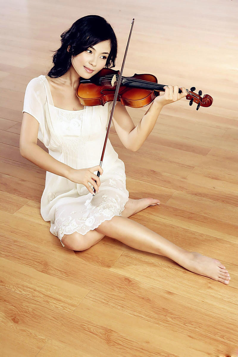 坐在木地板上拉小提琴的刘涛